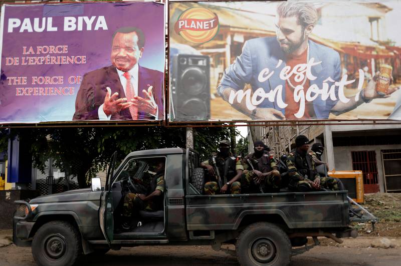Soldiers in a car driving past billboards with election messages
