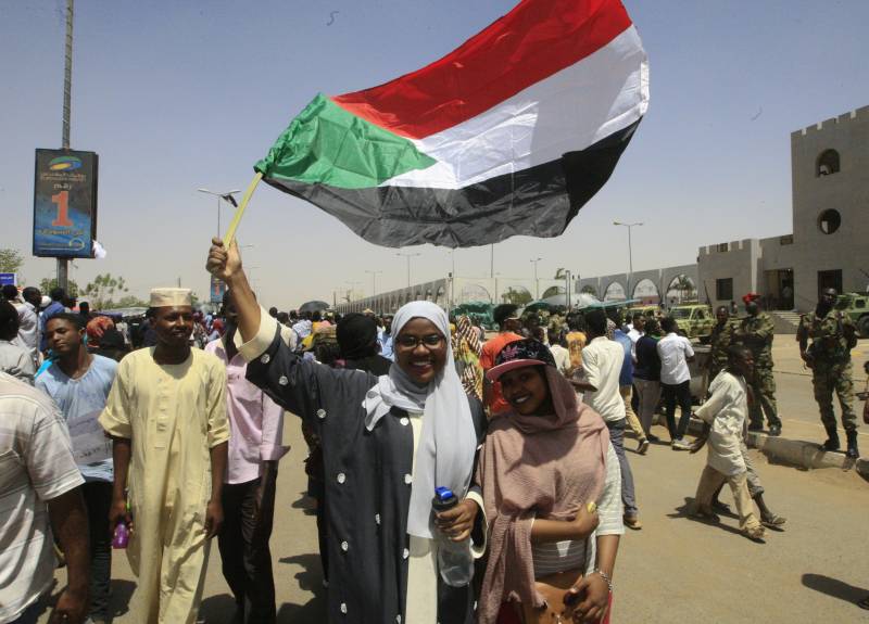 Women in a crowd waving a Sudanese flag