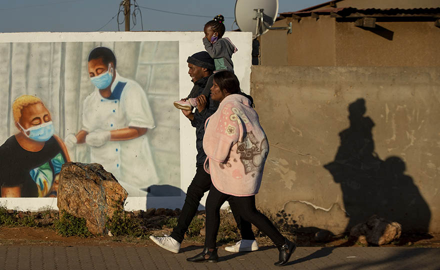 A family walks past a mural promoting vaccination for COVID-19 in Duduza township, east of Johannesburg, South Africa