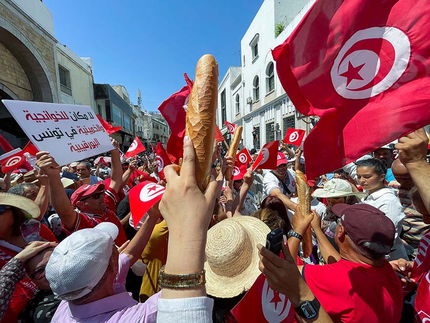 Demonstrators hold loaves of bread as they protest in opposition to a referendum on a new constitution called by President Kais Saied