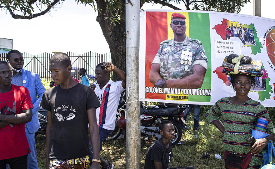 Supporters of junta leader, Colonel Mamady Doumbouya, stand around a poster of him at the Peoples Palace in Guinean capital Conakry, on September 11, 2021. 