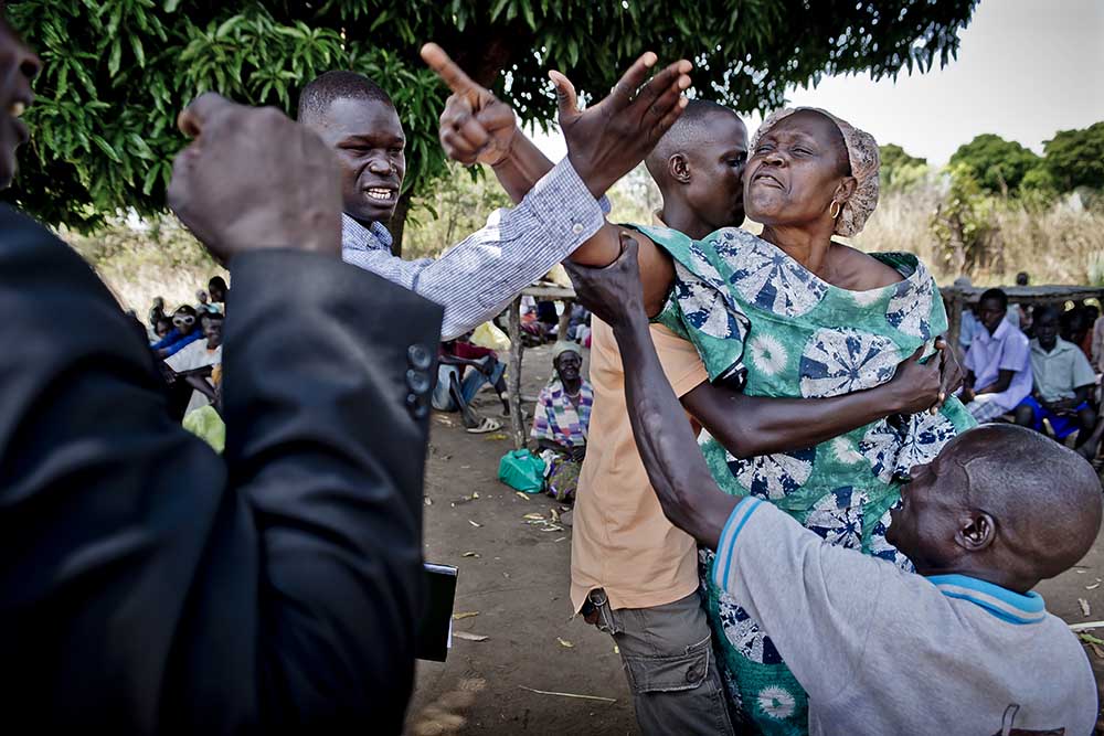 A woman in rural Uganda is shouting and pointing with her hand.