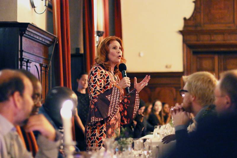 Woman talking in a microphone at a table in front of people