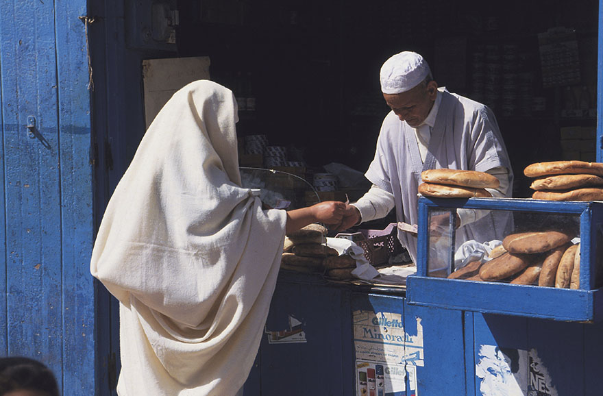 A person buying bread from a vendor.