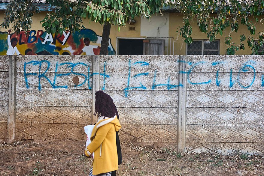 Chitungwiza, Zimbabwe, 30 August 2023. A woman walking past a wall with a painted message calling for “Fresh Elections”, referring to the main opposition party's demand for fresh elections that meet regional standards. Photo: Zinyange Auntony, AFP.
