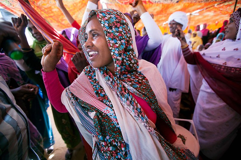 14 March 2013. Al Koma: Women and men dance traditional songs performed by a local singer in Al Koma village, North Darfur. Nearly 500 men and women in Al Koma village, some 80 kilometers west of El Fasher, celebrated International Women's Day in an event facilitated by UNAMID's Gender Advisory Unit and the Government of Sudan. Women leaders from North Darfur attended the event, which featured traditional nomadic songs and dances.