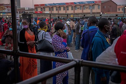 People in Harare, Zimbabwe, wait in line for public transport to ferry them home after work. 