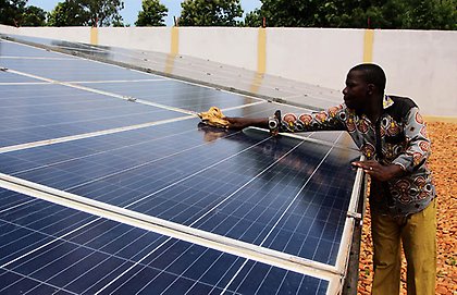 A technician cleans solar panels in Togo, part of the solar energy system used to provide electricity to Sikpe Afidegnon village, 