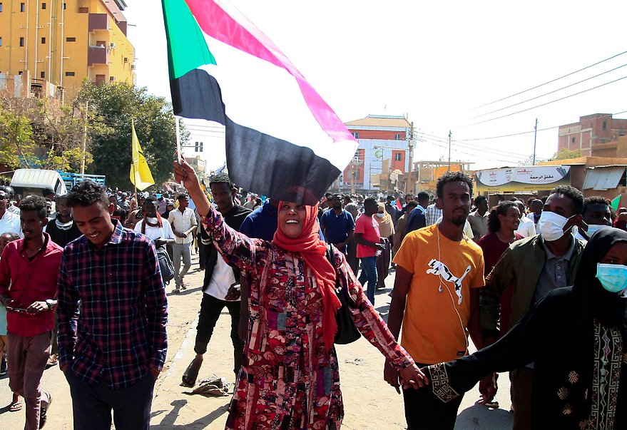 A Sudanese woman waves her country's national flag as she takes part in a rally to protest against last year's military coup