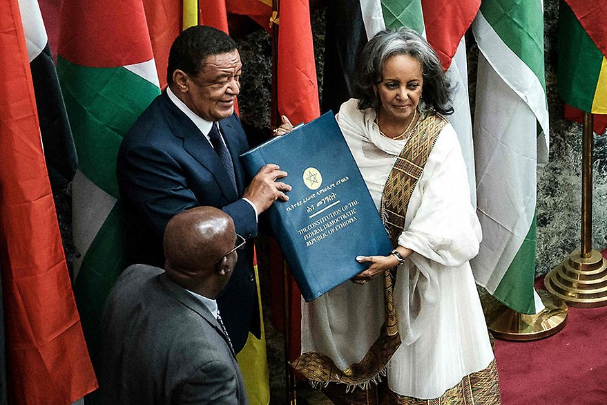 Ethiopia's first female President Sahle-Work Zewde recieves a book of the Constitution from former President Mulatu Teshomea at the Parliament in Addis Ababa on October 25, 2018